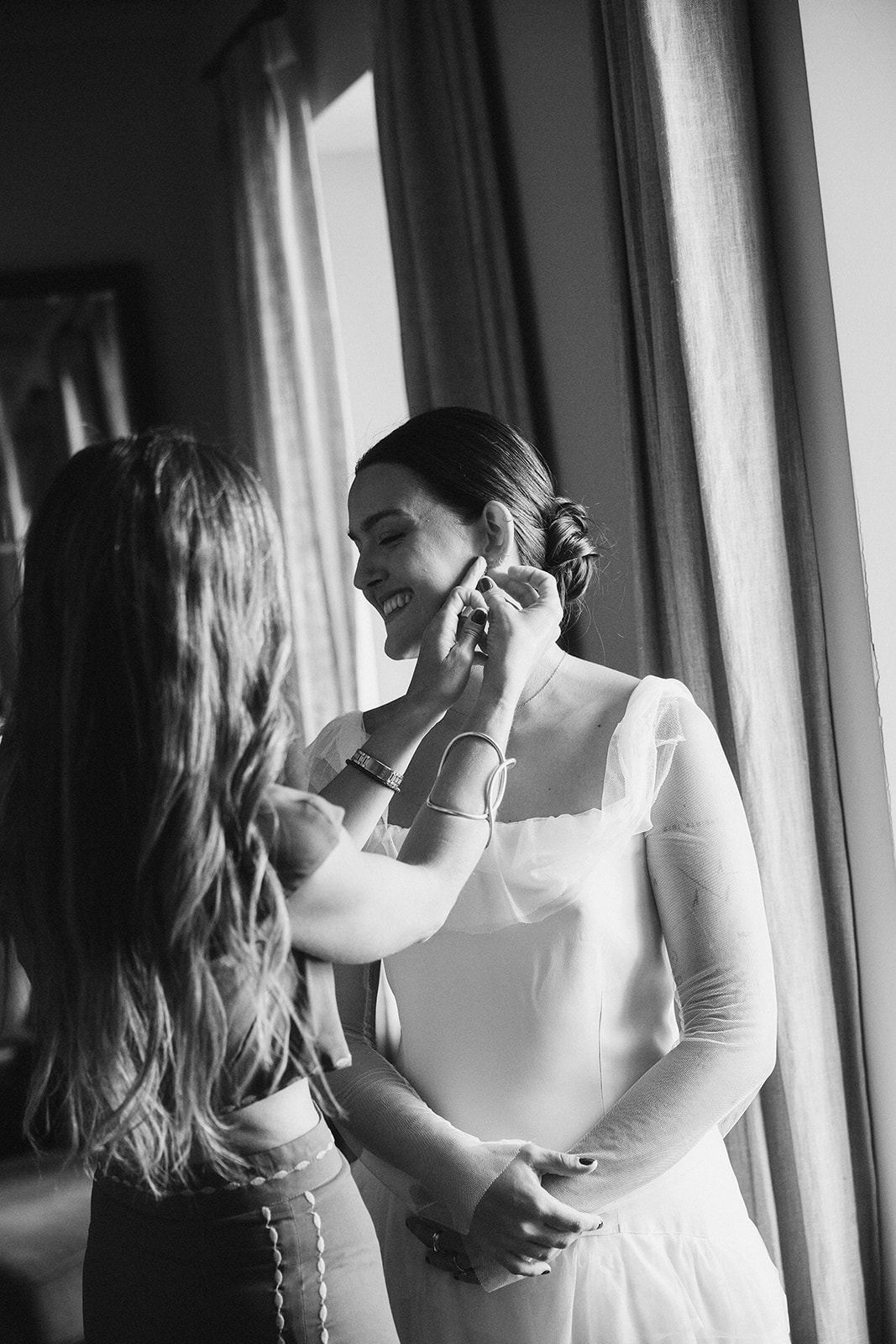Amiga colocando el pendiente a la novia, retrato en blanco y negro