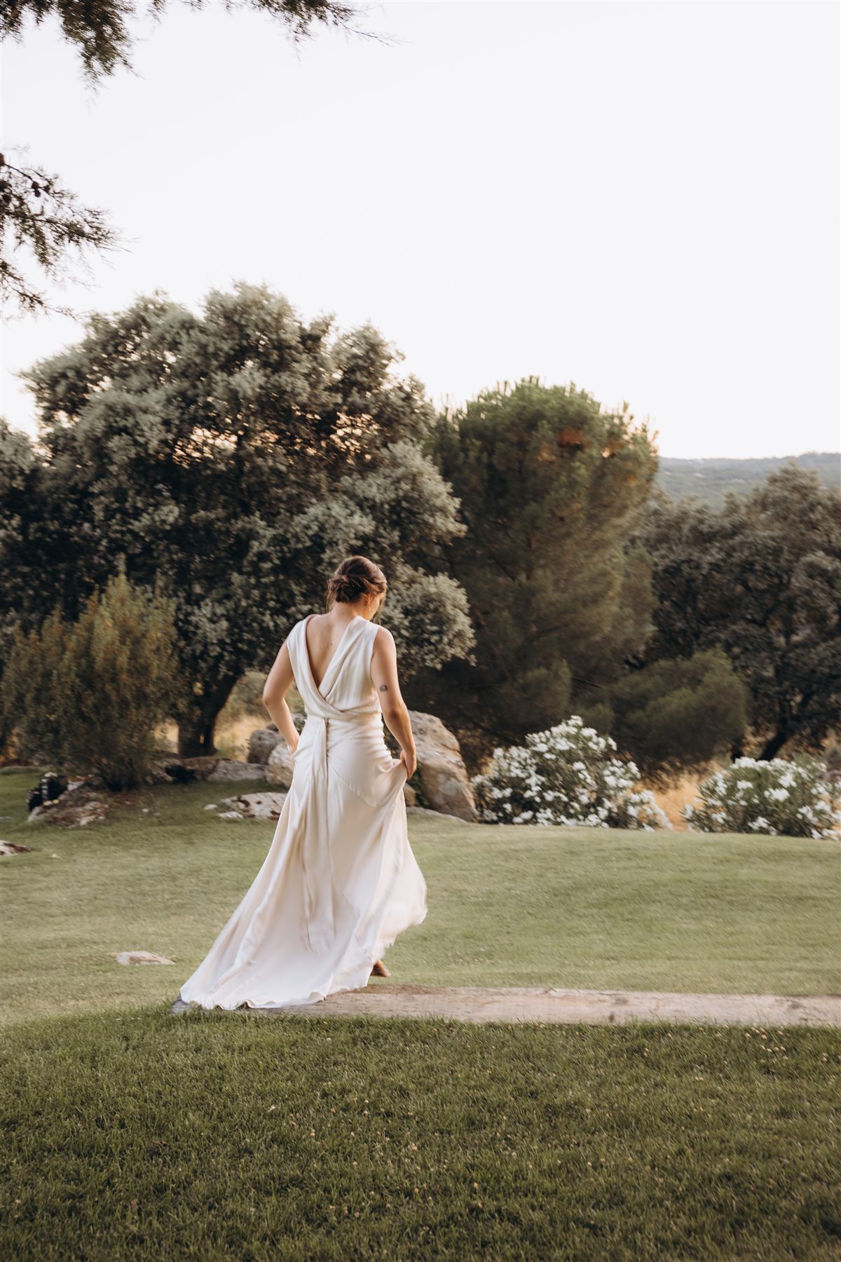 Novia caminando de espaldas en el jardín